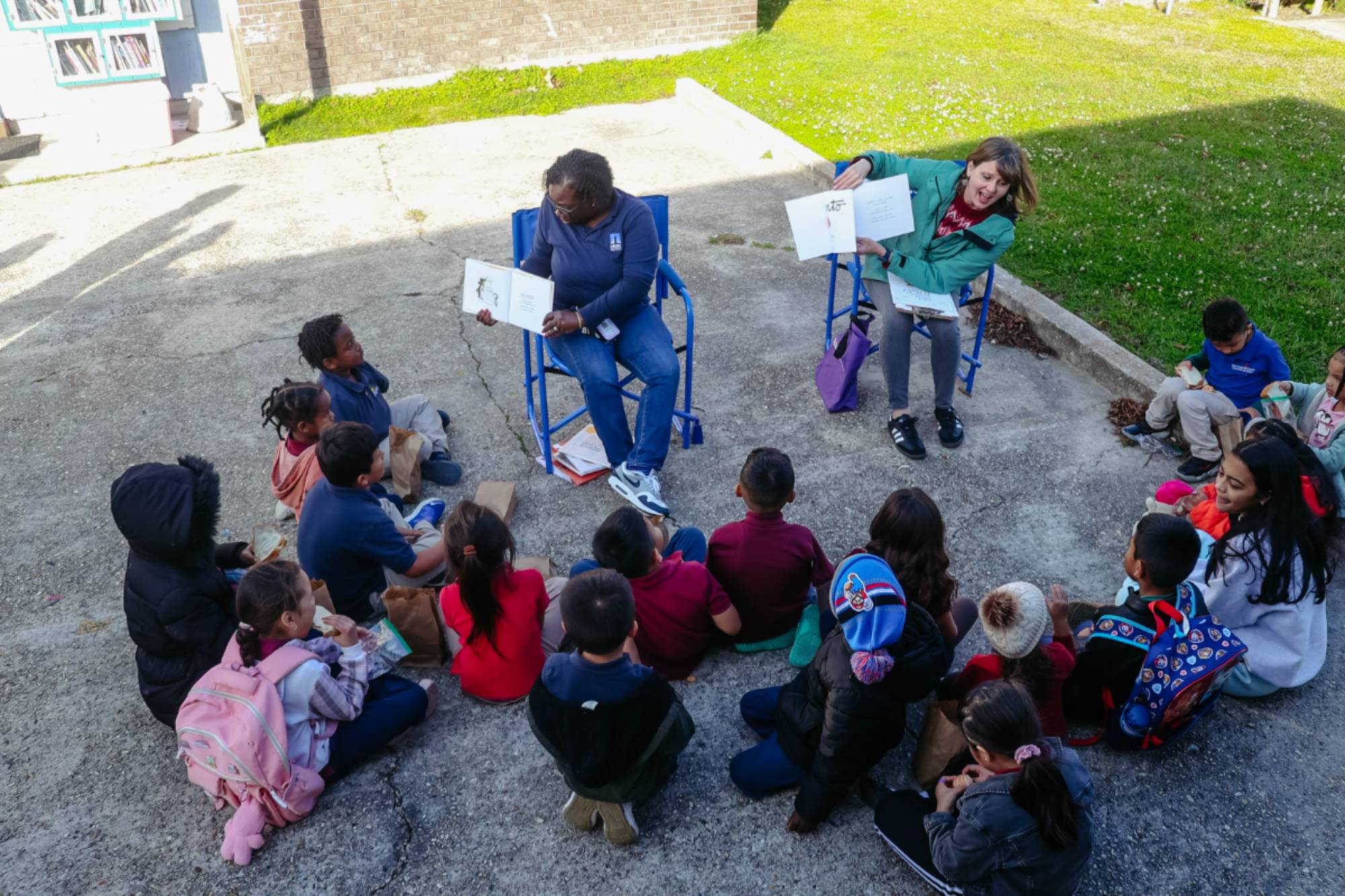 Story Hour in the Community Outdoor bilingual story time circle with LSU educators and children gathered around open books.