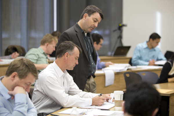 Instructor looks over students shoulder as he asks a question.