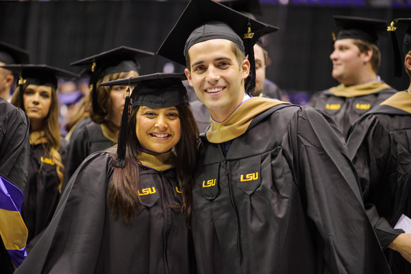 Graduates in caps and gowns at diploma ceremony.