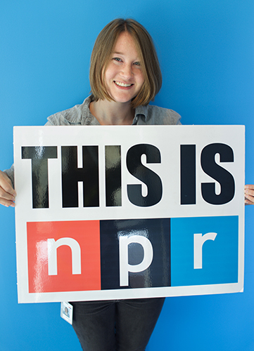 Photo of Mackenzie Roberts Beasley holding an sign with the words This is npr.